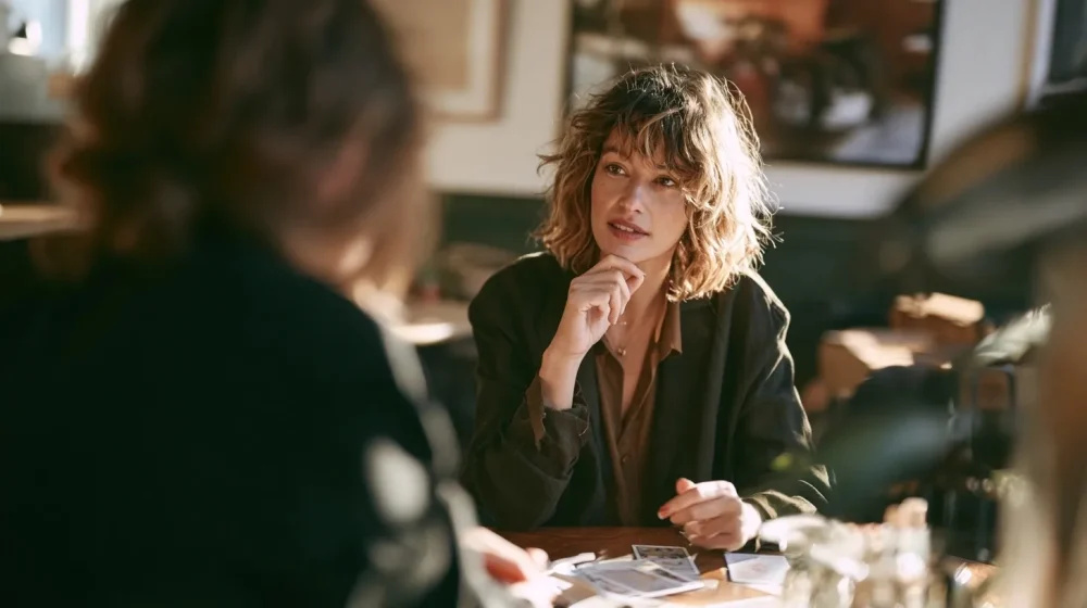 Pourquoi votre projet n’avance pas malgré vos idées — personne échangeant avec un prospect autour d une offre simple dans un café calme, style magazine professionnel